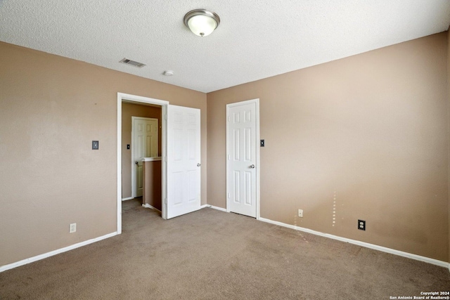 unfurnished room featuring carpet flooring and a textured ceiling