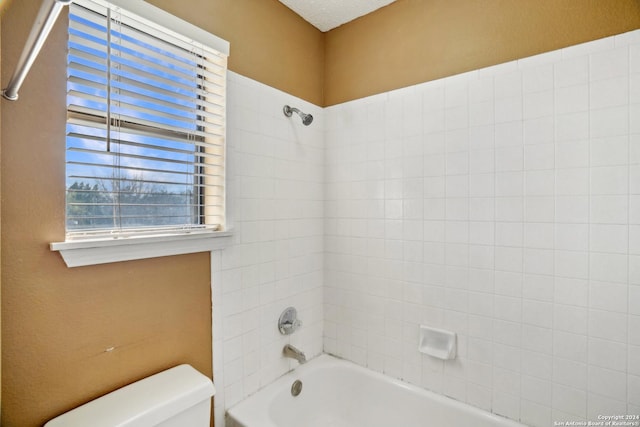 bathroom with tiled shower / bath combo and toilet