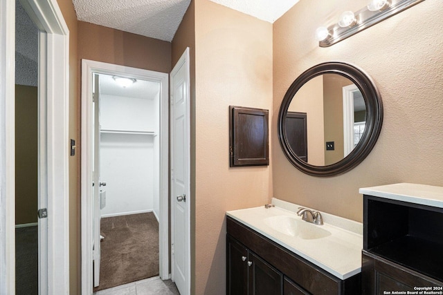 bathroom featuring tile patterned flooring, vanity, and a textured ceiling