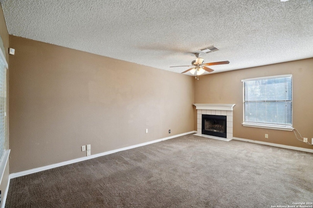 unfurnished living room featuring ceiling fan, a fireplace, carpet floors, and a textured ceiling