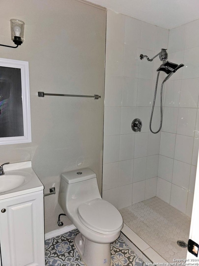 bathroom with tile patterned floors, vanity, toilet, and a tile shower