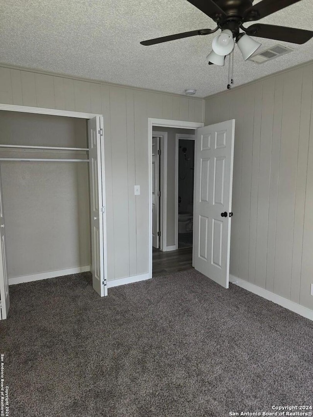 unfurnished bedroom featuring dark carpet, a textured ceiling, ceiling fan, and a closet