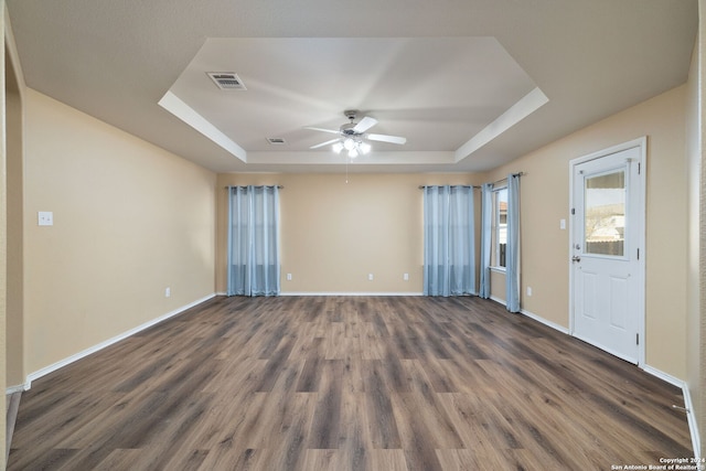 unfurnished room with dark hardwood / wood-style floors, a raised ceiling, and ceiling fan