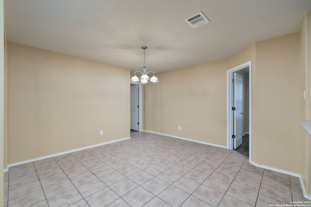 tiled spare room featuring a notable chandelier