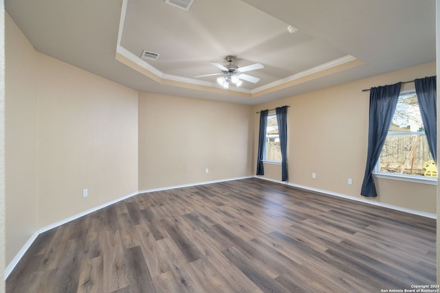 empty room featuring ornamental molding, a tray ceiling, ceiling fan, and dark wood-type flooring