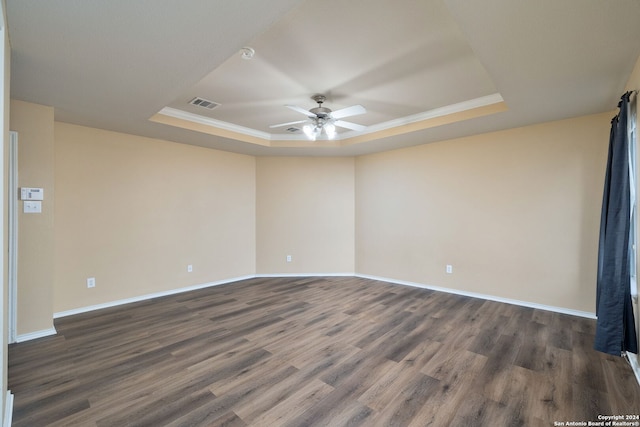 spare room featuring ceiling fan, a raised ceiling, dark wood-type flooring, and crown molding