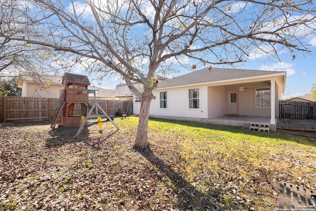 view of yard featuring ceiling fan, a deck, and a playground