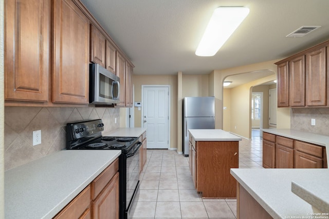 kitchen featuring backsplash, a center island, light tile patterned floors, and stainless steel appliances