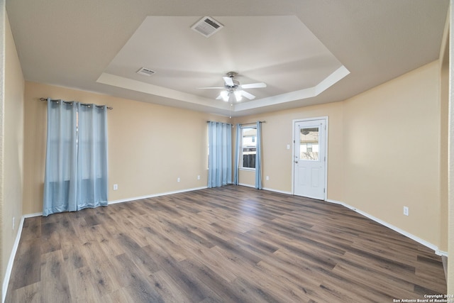 unfurnished room featuring ceiling fan, a raised ceiling, and wood-type flooring