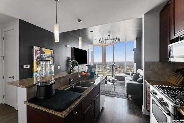 kitchen featuring dark brown cabinets, stainless steel appliances, sink, decorative light fixtures, and an island with sink