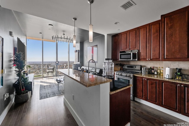 kitchen featuring floor to ceiling windows, backsplash, stone counters, hanging light fixtures, and appliances with stainless steel finishes