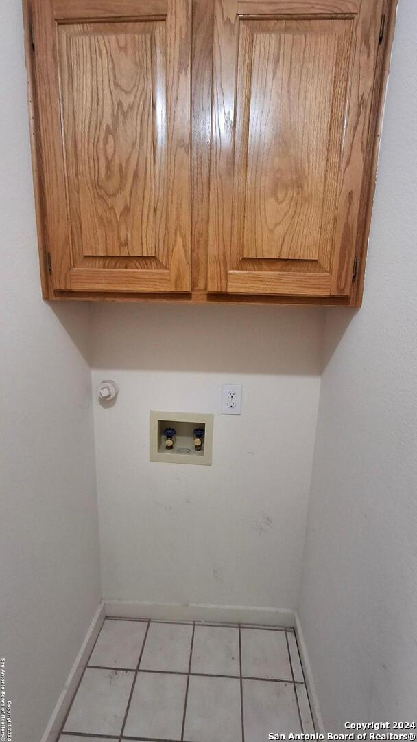 laundry room with hookup for a washing machine, cabinet space, baseboards, and light tile patterned floors