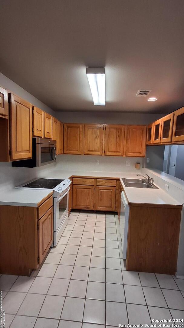 kitchen with light countertops, white appliances, a sink, and visible vents