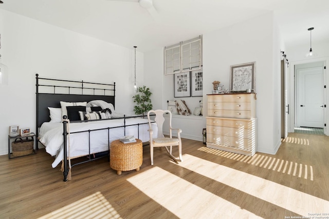 bedroom featuring a barn door and wood-type flooring