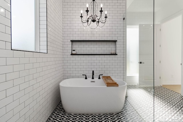 bathroom with a bath, tile walls, and a notable chandelier