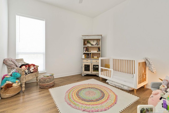 bedroom with hardwood / wood-style flooring and a nursery area