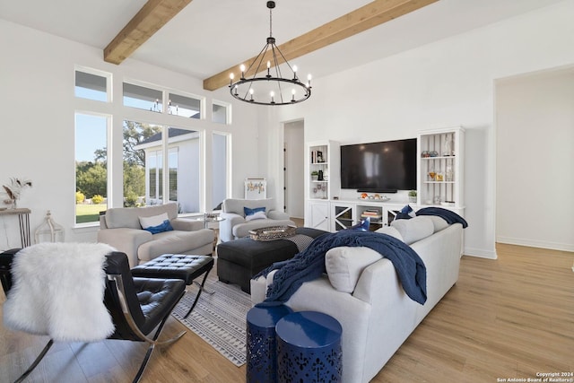 living room featuring beamed ceiling, light wood-type flooring, and an inviting chandelier