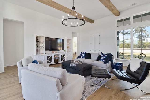 living room featuring beamed ceiling, a chandelier, and light wood-type flooring