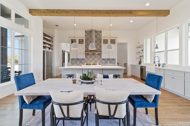 dining room featuring beamed ceiling, light wood-type flooring, and sink