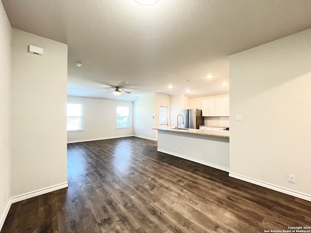 unfurnished living room featuring ceiling fan, sink, and dark wood-type flooring