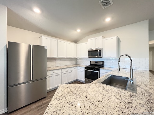 kitchen featuring light stone countertops, sink, stainless steel appliances, backsplash, and white cabinets