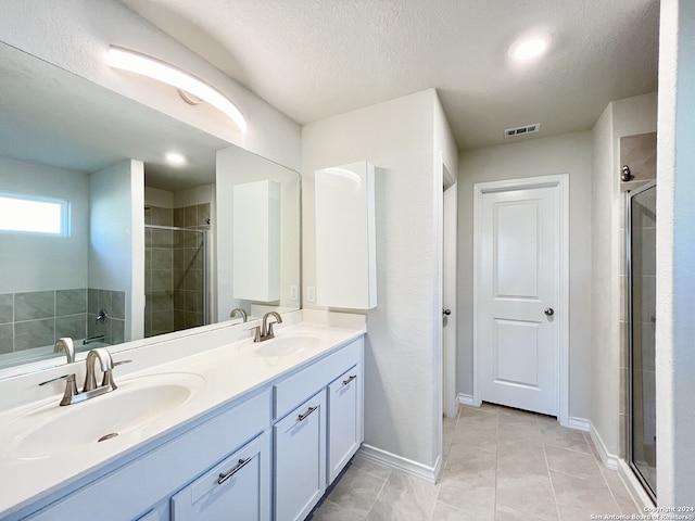 bathroom with tile patterned floors, vanity, an enclosed shower, and a textured ceiling