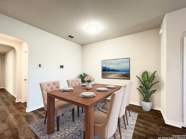 dining space featuring a textured ceiling and dark wood-type flooring