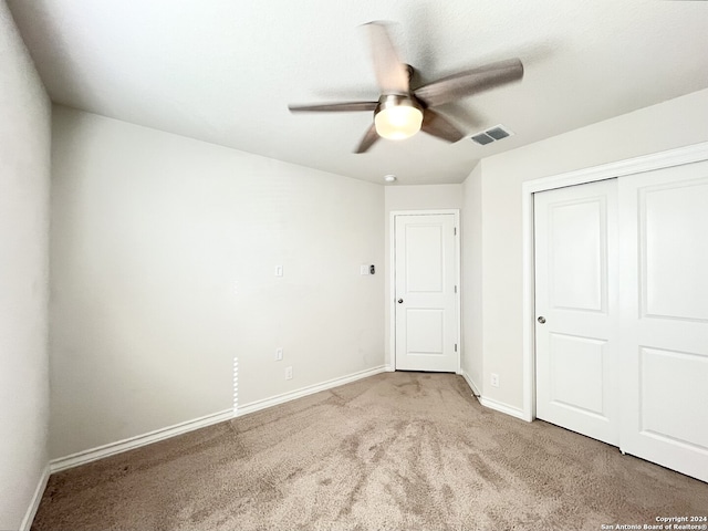 unfurnished bedroom with ceiling fan, a closet, and light carpet