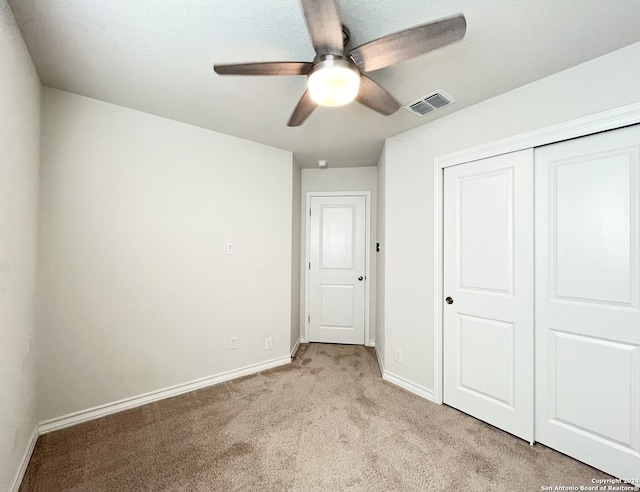 unfurnished bedroom with ceiling fan, light colored carpet, and a closet