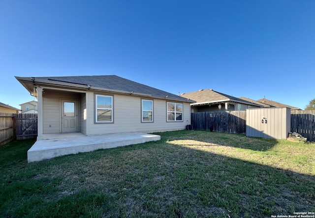 back of house featuring a lawn, a patio area, and a shed