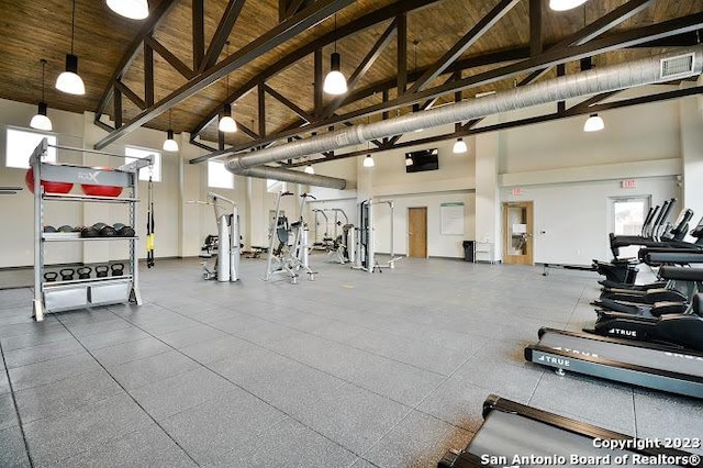 exercise room with high vaulted ceiling and wood ceiling