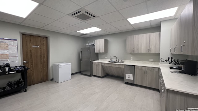 kitchen with stainless steel refrigerator, sink, refrigerator, light hardwood / wood-style floors, and a paneled ceiling