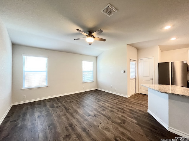 unfurnished living room featuring dark hardwood / wood-style flooring, vaulted ceiling, and ceiling fan