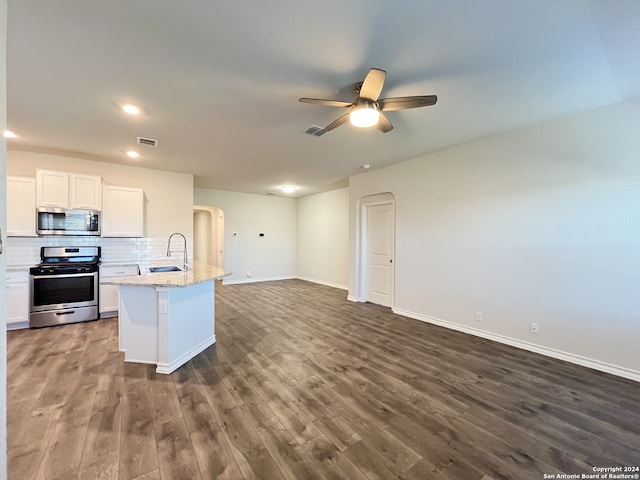 kitchen featuring decorative backsplash, an island with sink, appliances with stainless steel finishes, light stone counters, and white cabinetry