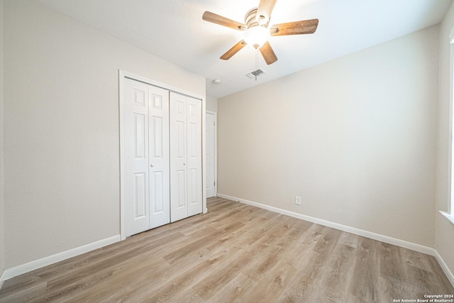 unfurnished bedroom featuring ceiling fan, light hardwood / wood-style flooring, and a closet