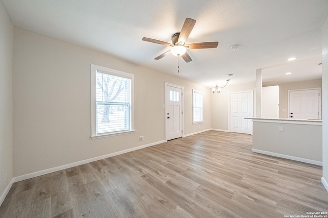 entrance foyer with plenty of natural light, ceiling fan with notable chandelier, and light hardwood / wood-style flooring