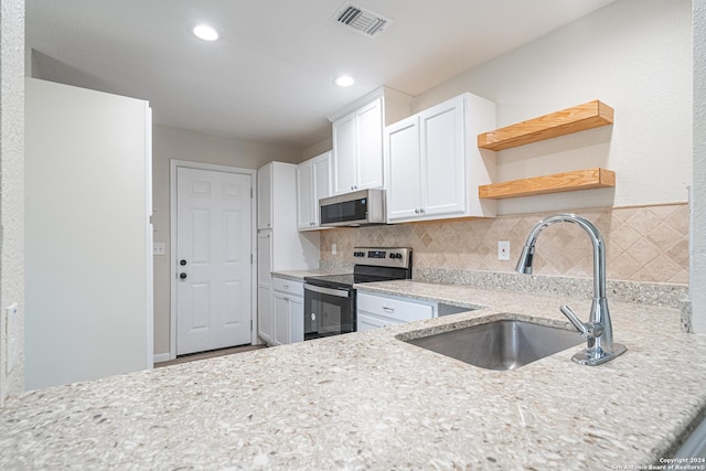 kitchen featuring appliances with stainless steel finishes, backsplash, light stone counters, sink, and white cabinets