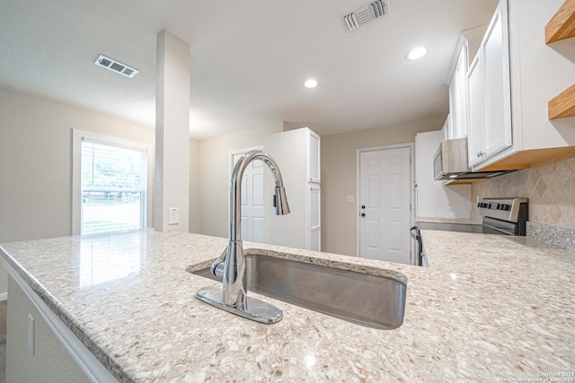 kitchen with white cabinetry, sink, tasteful backsplash, light stone counters, and stainless steel range with electric stovetop