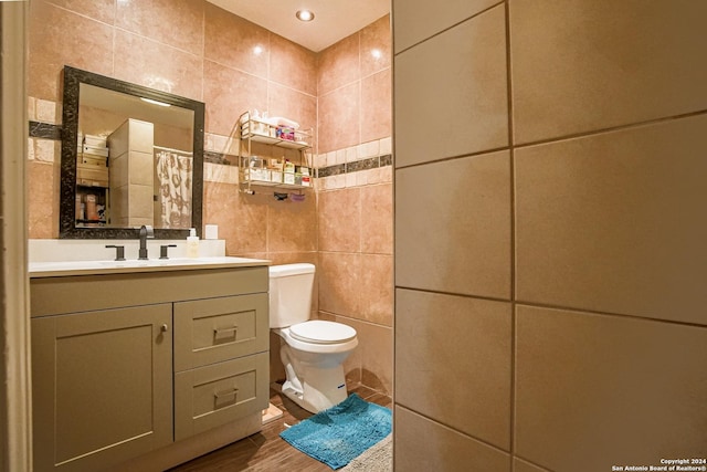 bathroom with vanity, toilet, and tile walls