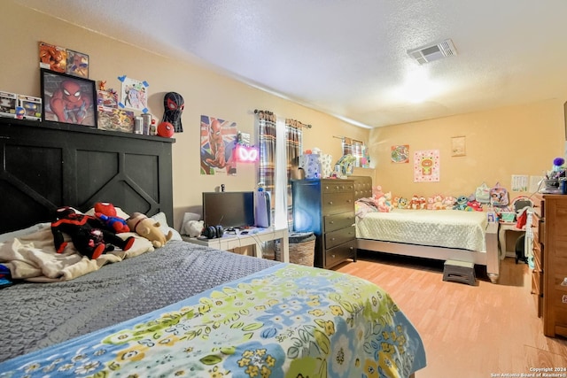 bedroom with a textured ceiling and light hardwood / wood-style flooring