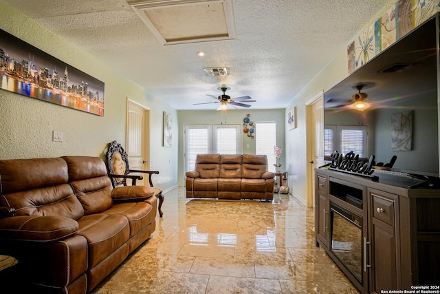 living room featuring ceiling fan and a textured ceiling