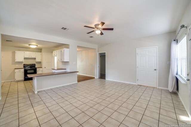 kitchen featuring white cabinets, kitchen peninsula, light tile patterned floors, and black electric range