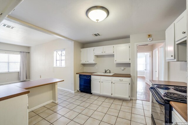 kitchen featuring white cabinetry, sink, light tile patterned flooring, and black appliances