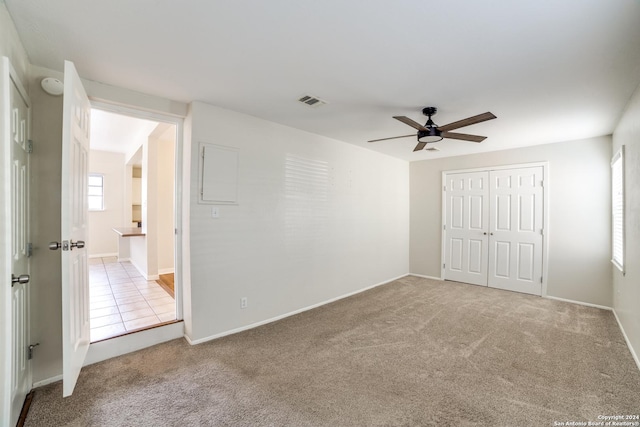 unfurnished bedroom with a closet, ceiling fan, and light colored carpet