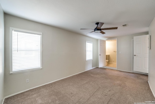 unfurnished bedroom with carpet flooring, ceiling fan, and ensuite bath