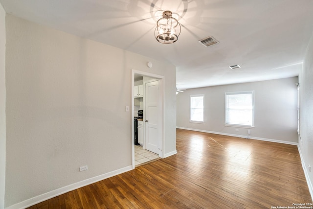 unfurnished room featuring ceiling fan with notable chandelier and light wood-type flooring