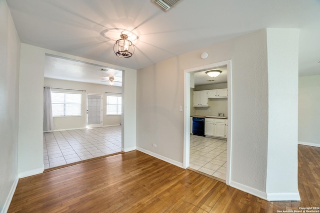 empty room featuring sink, light hardwood / wood-style floors, and ceiling fan with notable chandelier