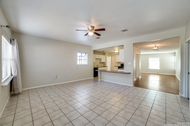 unfurnished living room with ceiling fan, light tile patterned floors, and a wealth of natural light