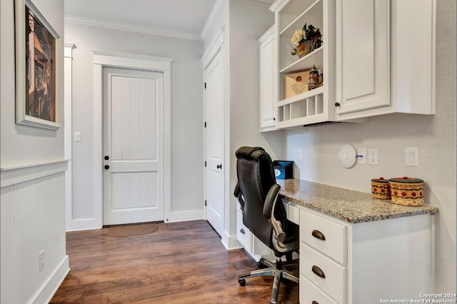 office with built in desk, dark wood-type flooring, and ornamental molding