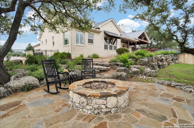 rear view of house with an outdoor fire pit and a patio